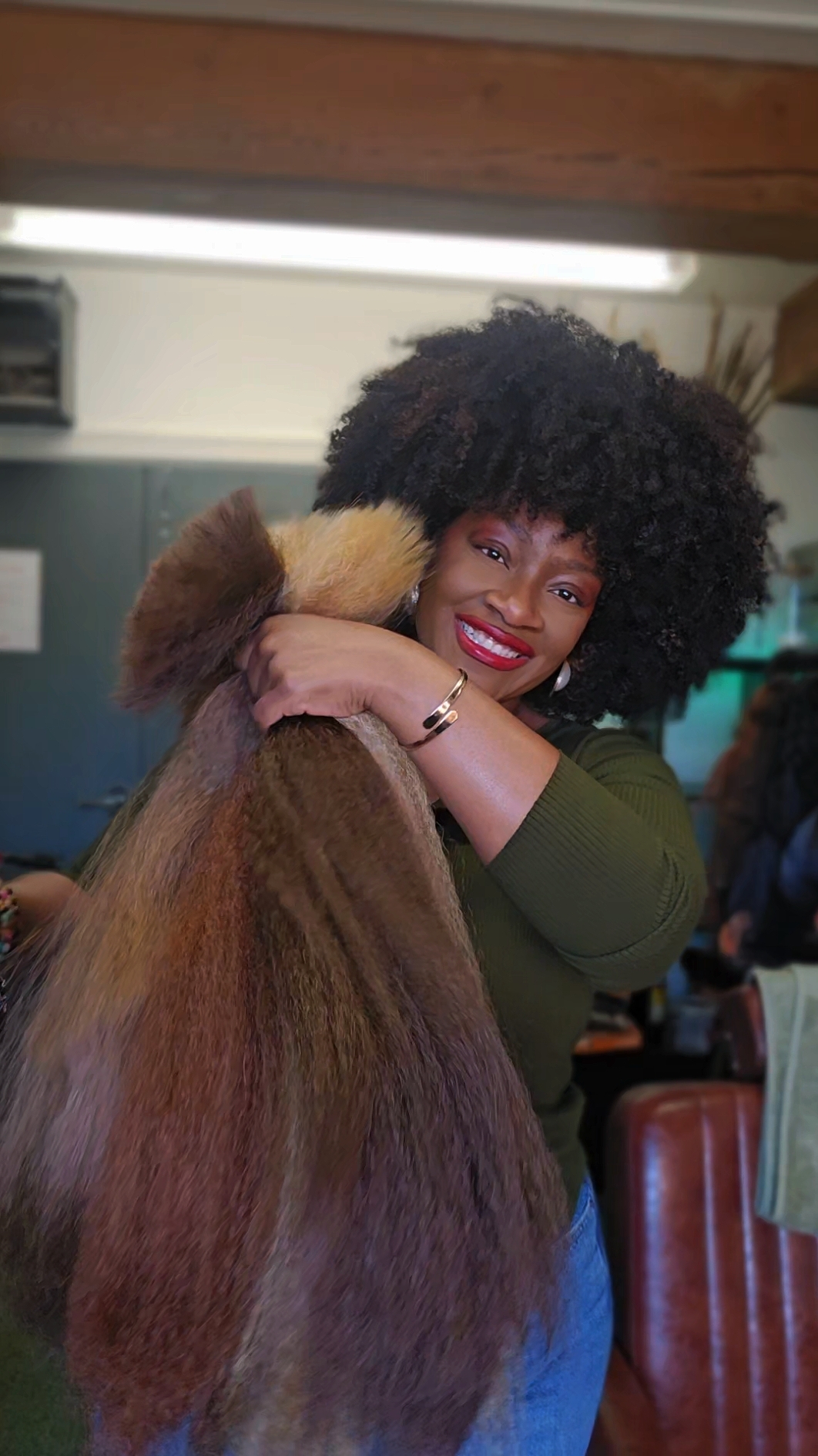 Kissa smiling while holding a long bundle of hair against her shoulder